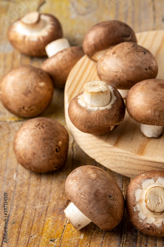 Top view of raw portobello mushrooms, on wooden board and rustic table, with selective focus, vertical