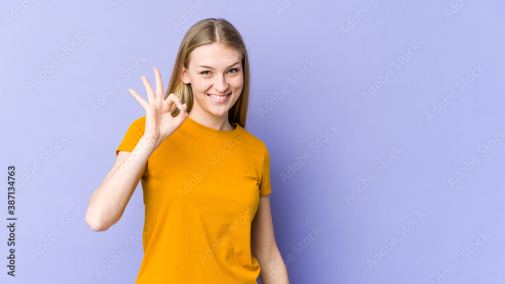 Young blonde woman isolated on purple background cheerful and confident showing ok gesture. Young blonde woman isolated on purple background cheerful and confident showing ok gesture.