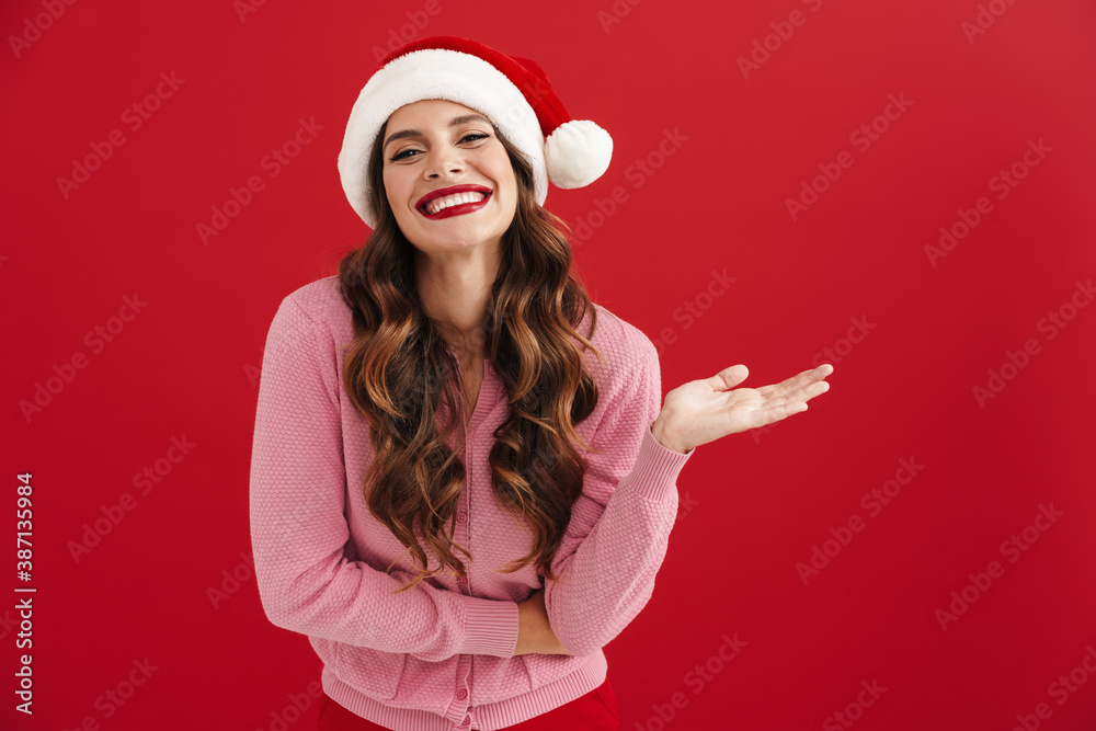 Beautiful happy girl in Santa Claus hat smiling and showing copyspace Beautiful happy girl in Santa Claus hat smiling and showing copyspace