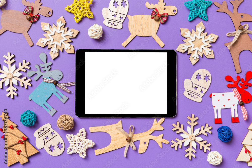 Festive decorations and toys on purple background. Top view of digital tablet. Merry Christmas concept Festive decorations and toys on purple background. Top view of digital tablet. Merry Christmas concept