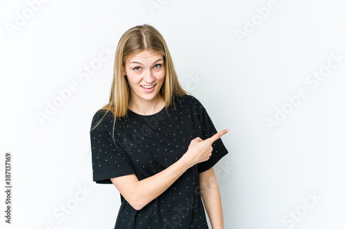 Young blonde woman isolated on white background smiling and pointing aside  showing something at blank space.