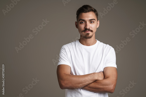 Image of caucasian unshaven guy posing on camera with arms crossed