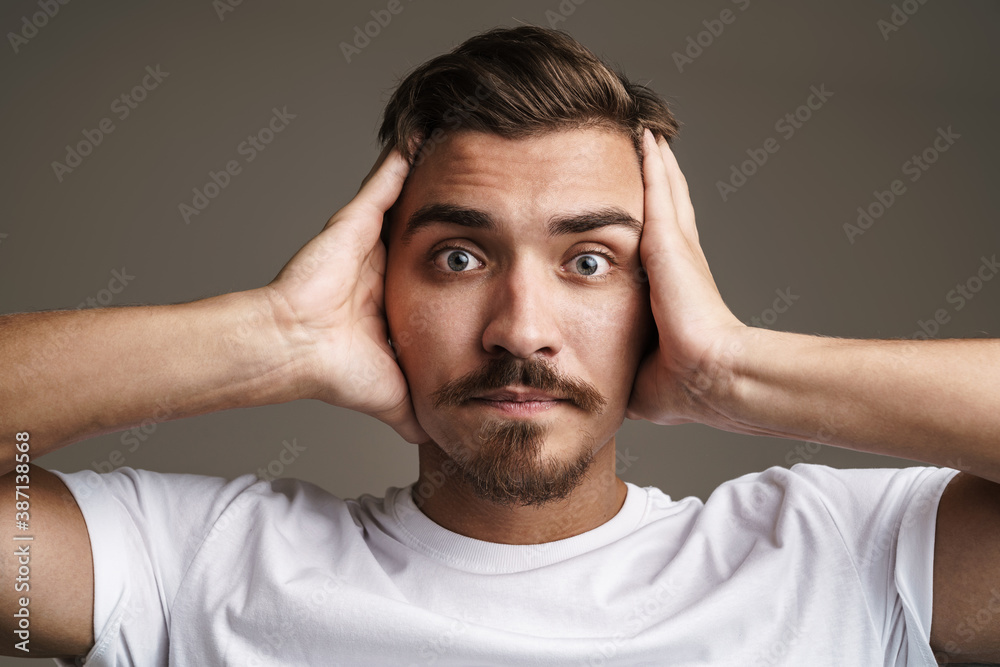 Image of shocked unshaven guy expressing surprise and grabbing her head Image of shocked unshaven guy expressing surprise and grabbing her head