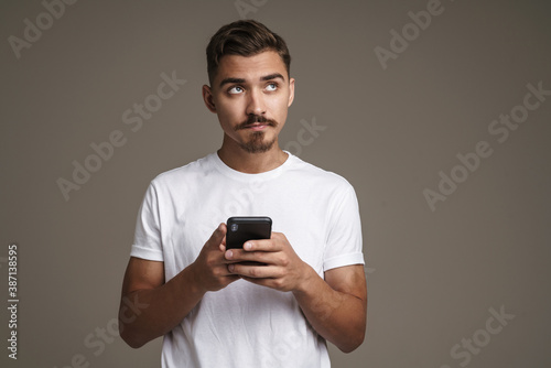 Image of thinking unshaven guy using mobile phone