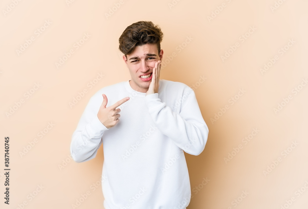 Young caucasian man isolated on beige background having a strong teeth pain, molar ache. Young caucasian man isolated on beige background having a strong teeth pain, molar ache.