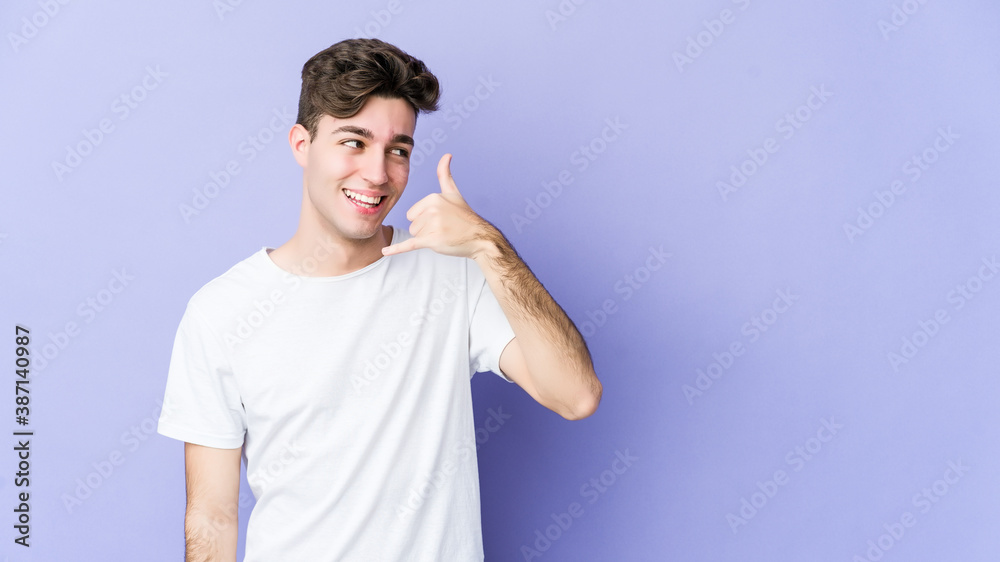 Young caucasian man isolated on purple background showing a mobile phone call gesture with fingers. Young caucasian man isolated on purple background showing a mobile phone call gesture with fingers.