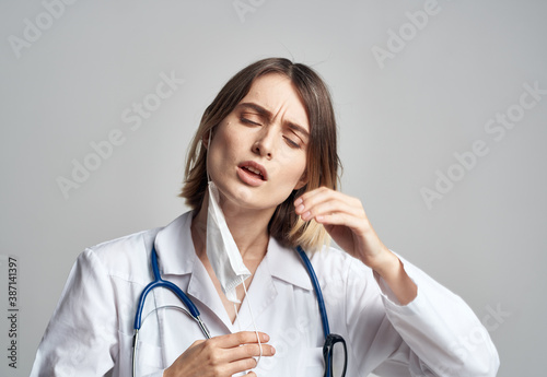 Doctor professional with a stethoscope and in a medical gown on a light background medical mask