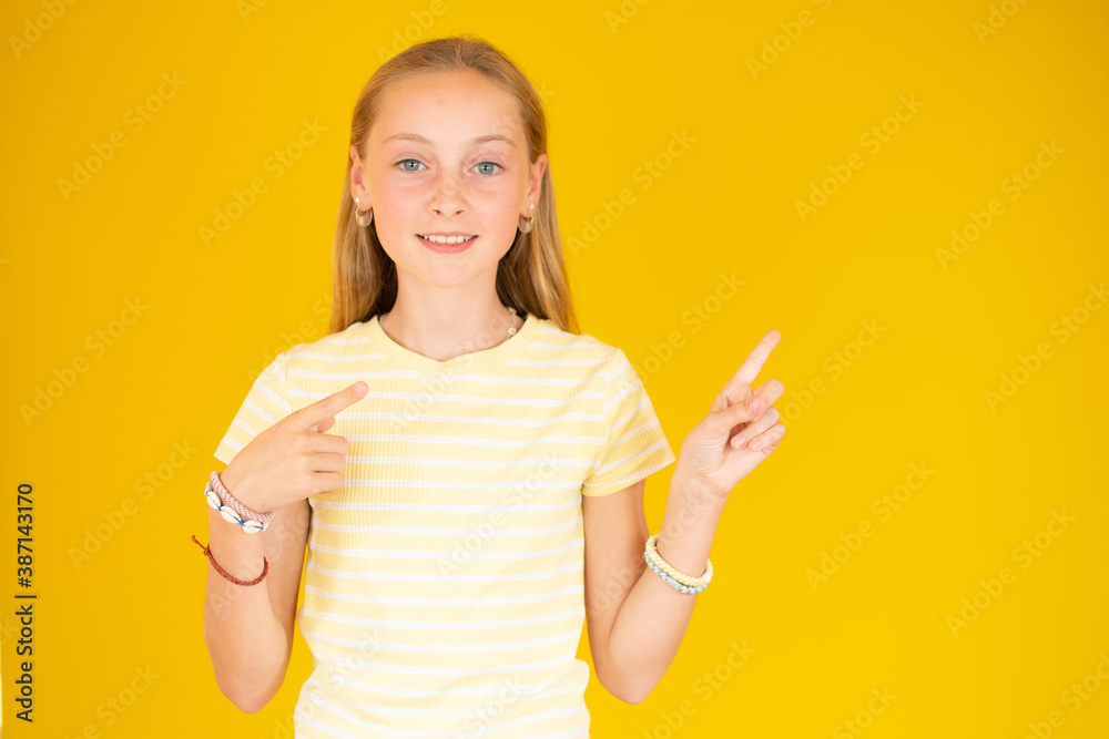 Happy girl showing finger away over yellow background. Looking at camera Happy girl showing finger away over yellow background. Looking at camera