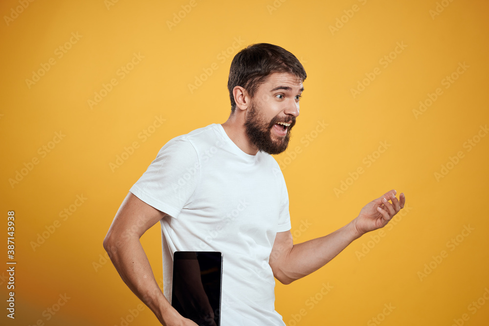 Man with a tablet on a yellow background in a white t-shirt new technologies businessman touch screen touchpad