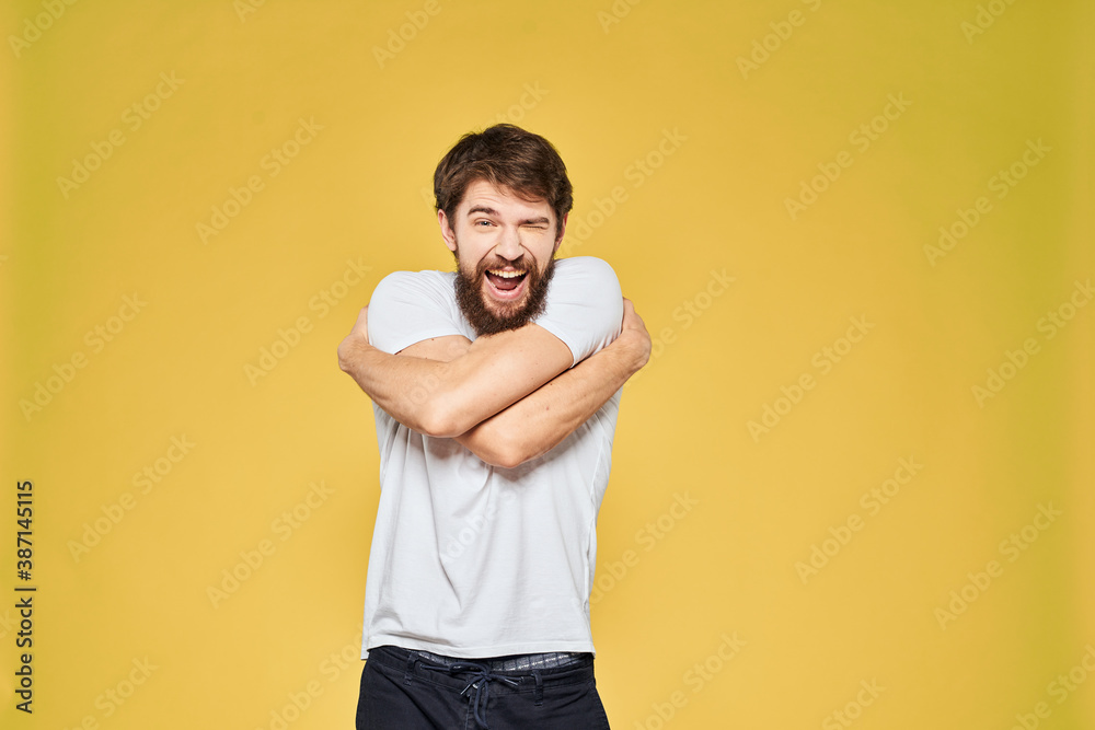 Man gesturing with hands emotions lifestyle white t-shirt yellow isolated background Man gesturing with hands emotions lifestyle white t-shirt yellow isolated background