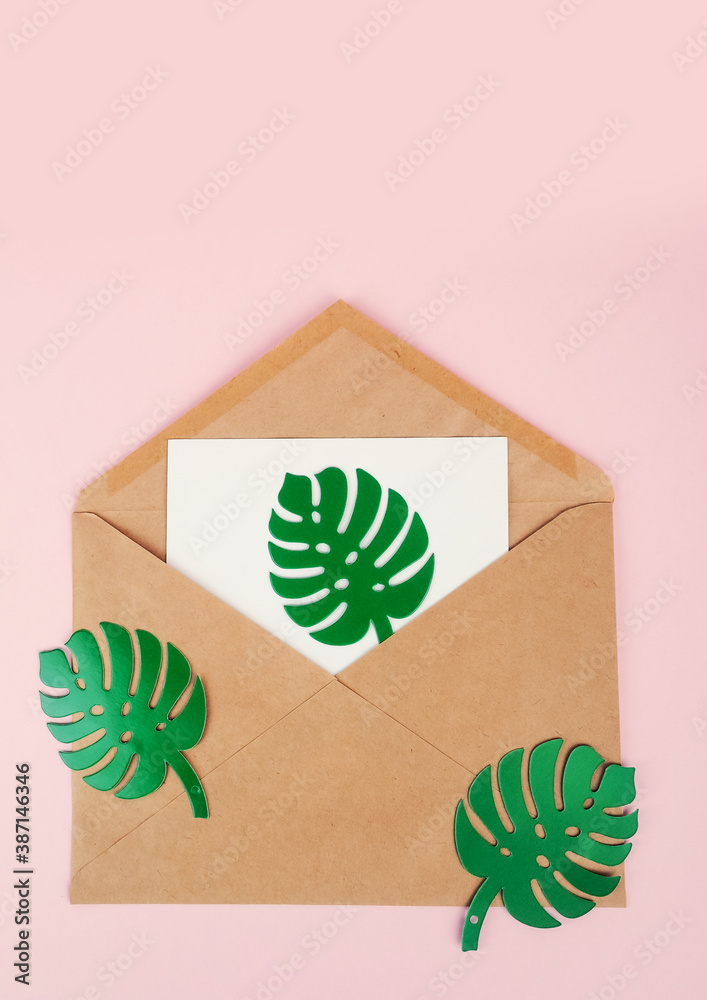 Blank white envelope on paper monstera sheet on pink background Blank white envelope on paper monstera sheet on pink background