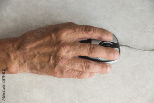 Close-up of an elderly man's hand on a computer mouse. older people are learning new computer technologies. Selective focus, shallow depth of field