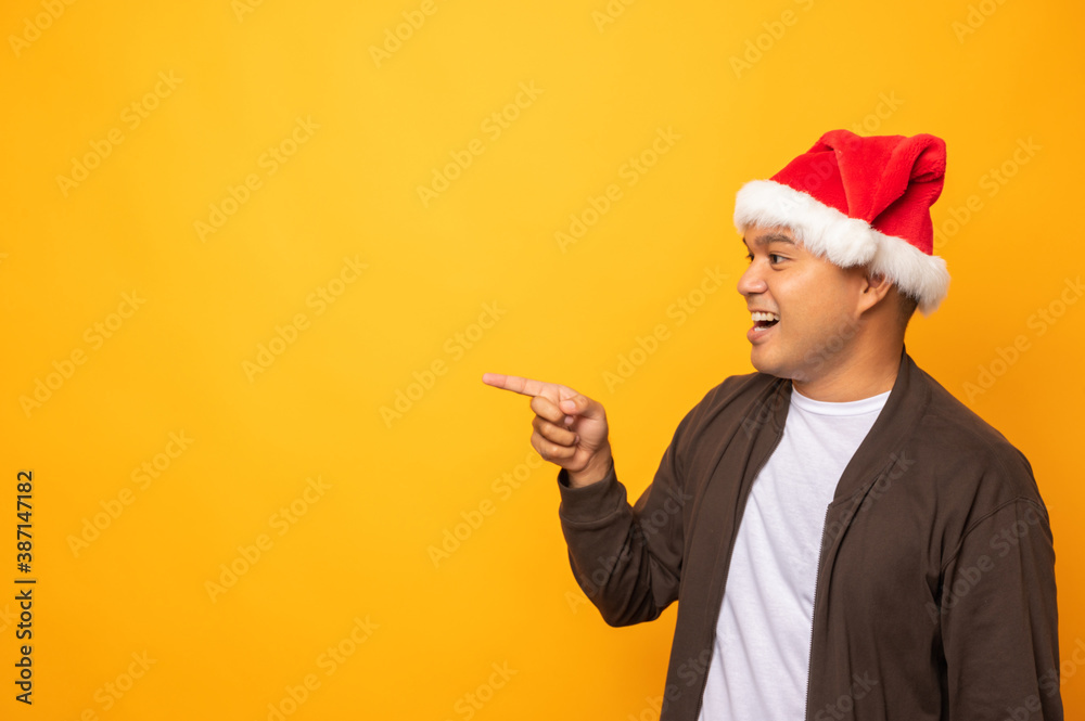 Young handsome asian man wearing christmas hat and pointing fing Young handsome asian man wearing christmas hat and pointing fing
