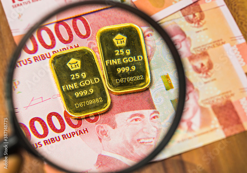 Profile of Fine Gold 25 gram produced by Aneka Tambang, an Indonesian government company, on rupiah money background. photo