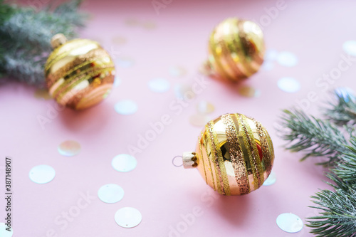Golden Christmas balls and fir branches on a pink background with copy space.