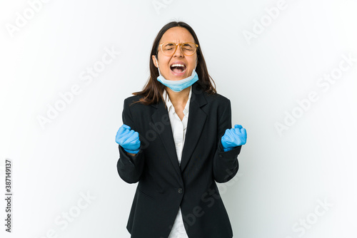 Young business latin woman wearing a mask to protect from covid isolated on white background cheering carefree and excited. Victory concept.