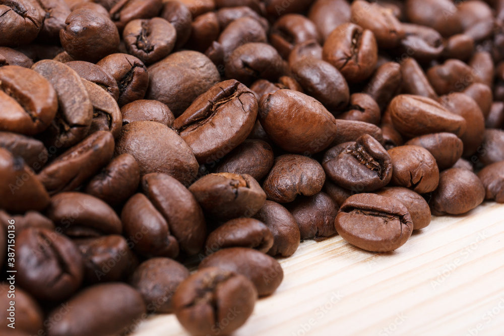 Obraz premium Fresh roasted coffee beans on wooden table. Macro shot.