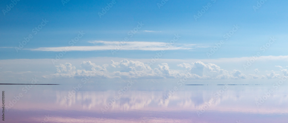 Pink salt lake water with clouds and blue sky