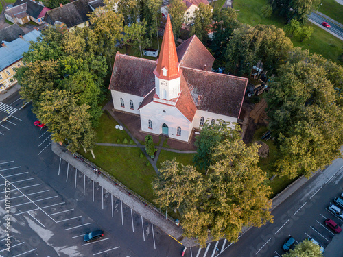 Top down view on Lutheran church with trees surrounding it, half empty parking lot next to it