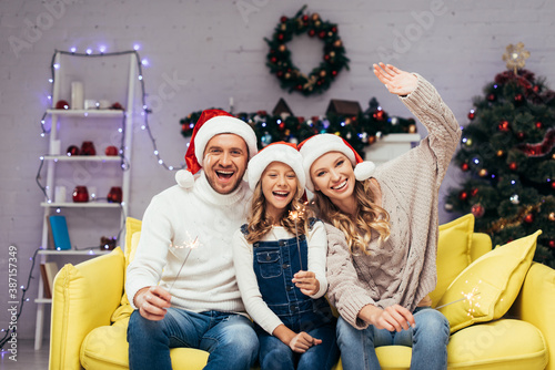 joyful family in santa hats holding sparklers in decorated living room © LIGHTFIELD STUDIOS