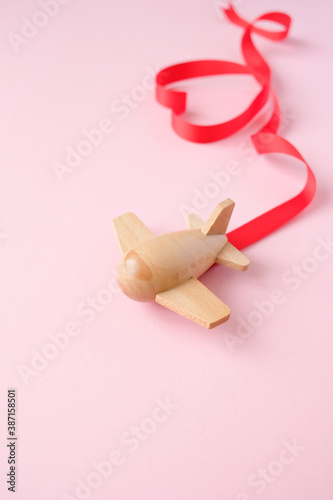 small wooden toy airplane lucky with red ribbon in the shape of heart