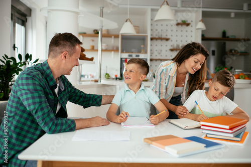 Parents helping the kids with their homework. Litlle boys learning at home
