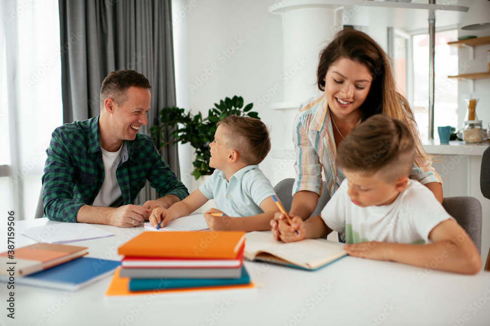 Parents helping the kids with their homework. Litlle boys learning at home Parents helping the kids with their homework. Litlle boys learning at home