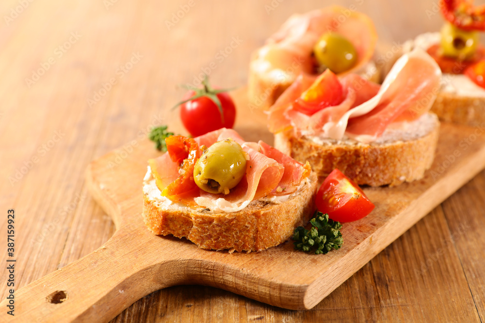 tapas- bread slice with cheese, prosciutto and olive