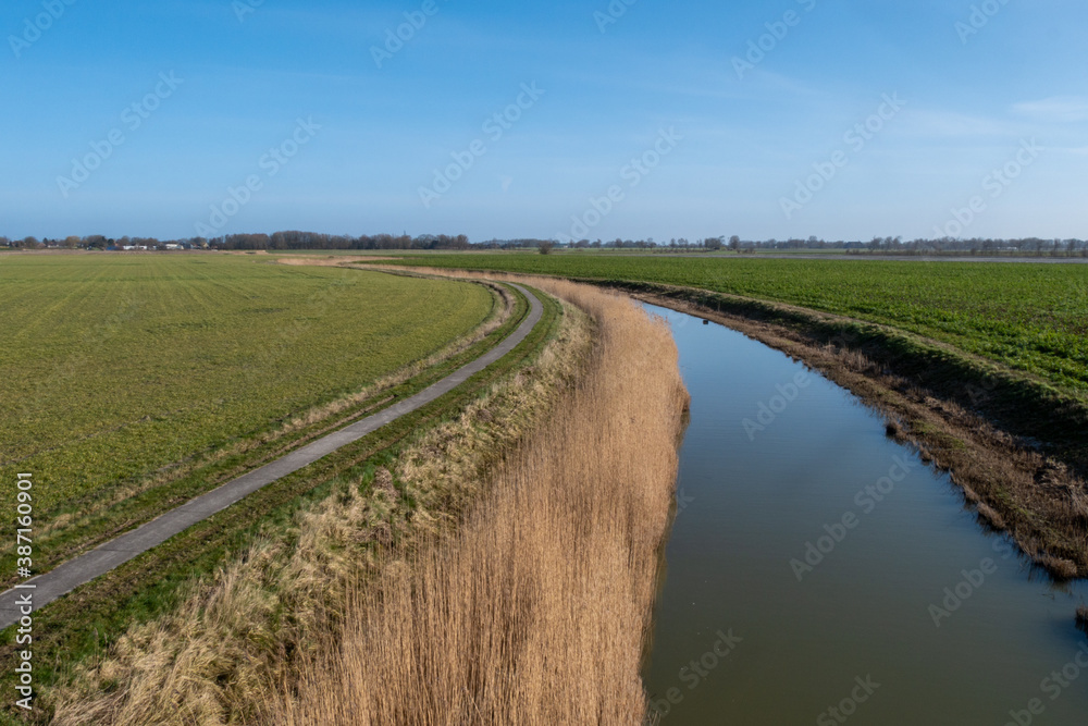 canal in the netherlands with grass and a road making a turn canal in the netherlands with grass and a road making a turn