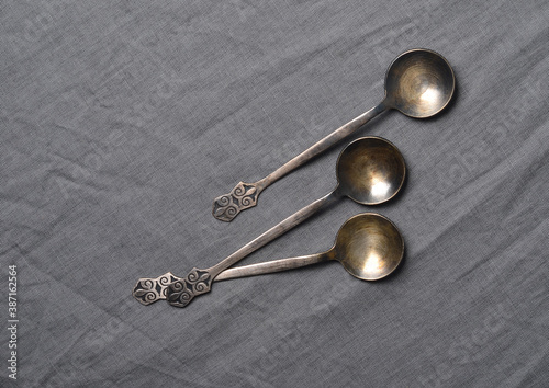 Ancient metal tablespoons on grey fabric close-up