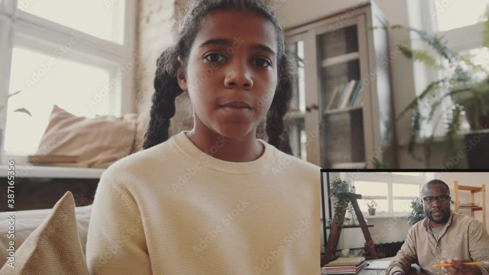Video call interface of little Afro-American speaking with male teacher ...