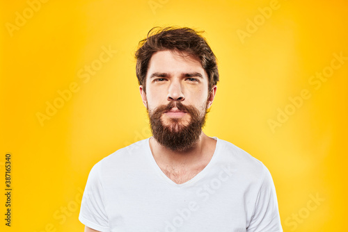 emotional bearded man in t-shirt cropped view yellow background studio