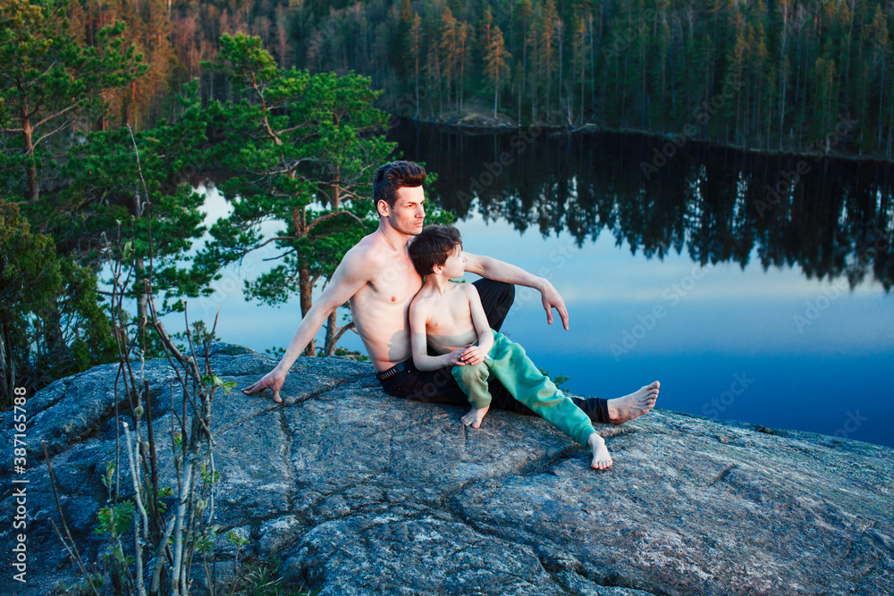 Fototapeta premium middle age man with little cute son doing sport yoga on the top of the mountain together, happy family lifestyle people outdoor, summer wild nature for training