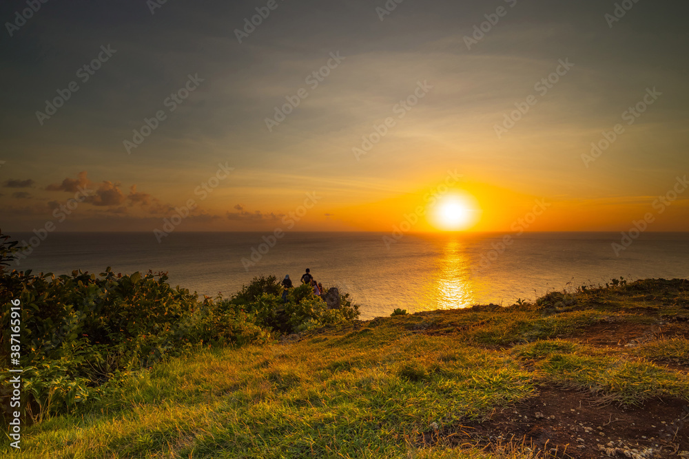 Seascape. Spectacular view from Uluwatu cliff in Bali. Sunset time. Golden hour. Bright sunlight on the horizon. Silhouettes of people. Nature concept. Soft focus. Slow shutter speed. Seascape. Spectacular view from Uluwatu cliff in Bali. Sunset time. Golden hour. Bright sunlight on the horizon. Silhouettes of people. Nature concept. Soft focus. Slow shutter speed.