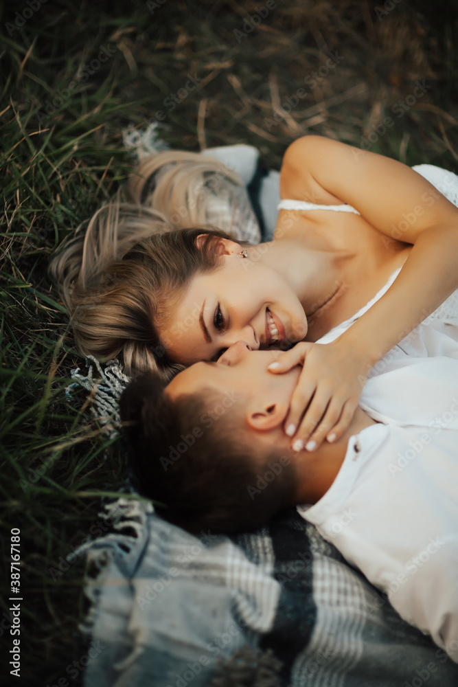 Young happy couple lying on blanket on green grass. They relaxing on picnic blanket outdoor. Close up. Young happy couple lying on blanket on green grass. They relaxing on picnic blanket outdoor. Close up.