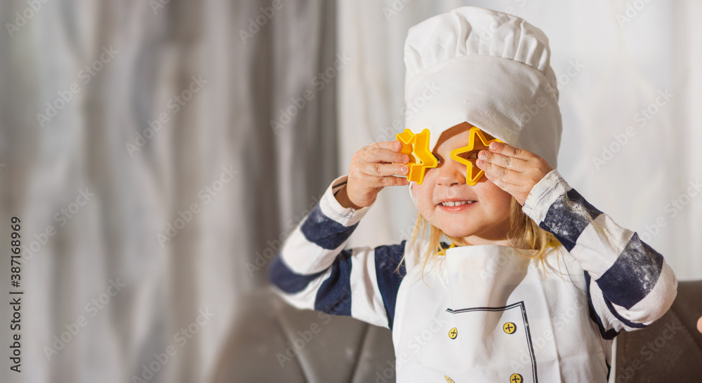 Little girl baking biscuits looking through star - cookie cutter Little girl baking biscuits looking through star - cookie cutter