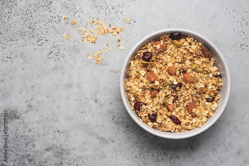 Homemade granola with oatmeal, nuts, dried fruits in a bowl on a gray background. Fast and healthy breakfast concept