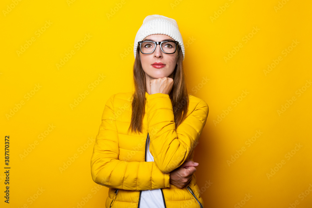 Pensive young woman holding her chin with hand on yellow background. Pensive young woman holding her chin with hand on yellow background.