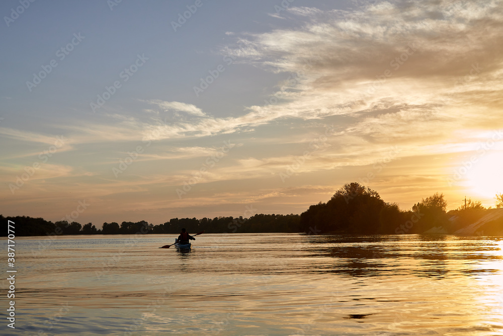 Sillouette of man kayaking on the Danube river at sunset