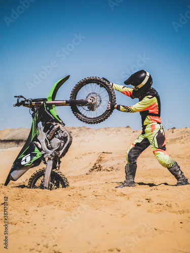 Fototapeta Naklejka Na Ścianę i Meble -  A motorcyclist pulls a motorcycle. Drags a motorcycle into the sand. Dirtbike 
