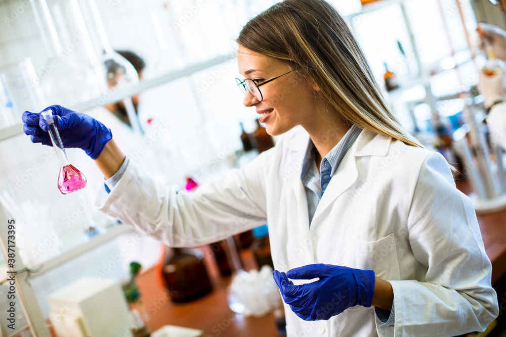 Young female scientist examining liquid in biochemical lab Young female scientist examining liquid in biochemical lab