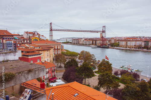 Biscay bridge flying with gondola over river Nervion, toned. Portugalete landmark. Famous bridge called Puente de Vizcaya near Bilbao. Traffic and transfer concept. Riverbank of Portugalete in autumn. photo