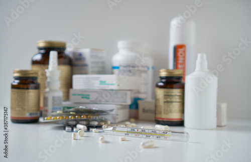 Bottle pills and medicine capsule on table, drugs and tablets boxes in background. Medical thermometer with a temperature of 38 degrees. Increased body temperature of a sick person. 