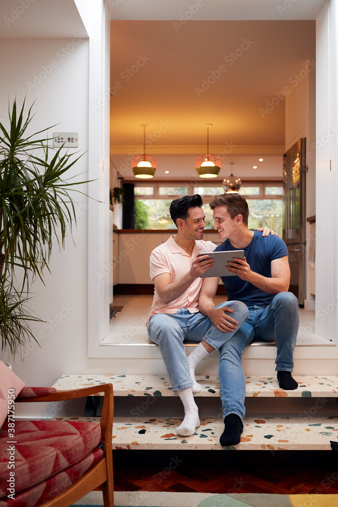 Fototapeta premium Loving Same Sex Male Couple Using Digital Tablet As They Relax At Home Together