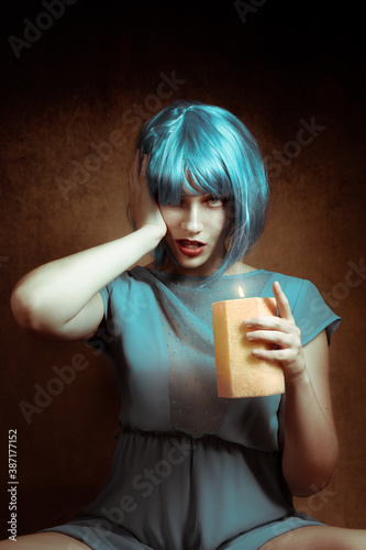 Pretty woman wearing costume of blue devil in Halloween wearing blue wig and holding a candle photo