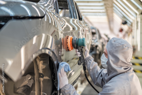 Wallpaper Mural An employee of the car body paint shop with a medical mask on his face polishes the painted surface Torontodigital.ca