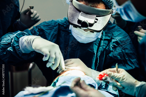 Close up doctor with surgical tools making surgery in the operating room, baldness treatment, hair transplant