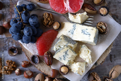 Selective focus. Cheese, nuts and fruits. Cheese snack on a wooden stand. Wine appetizer.