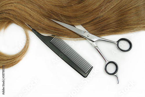 Hairdresser tools and curl of hair isolated on white background. Scissor and comb. Beauty concept.