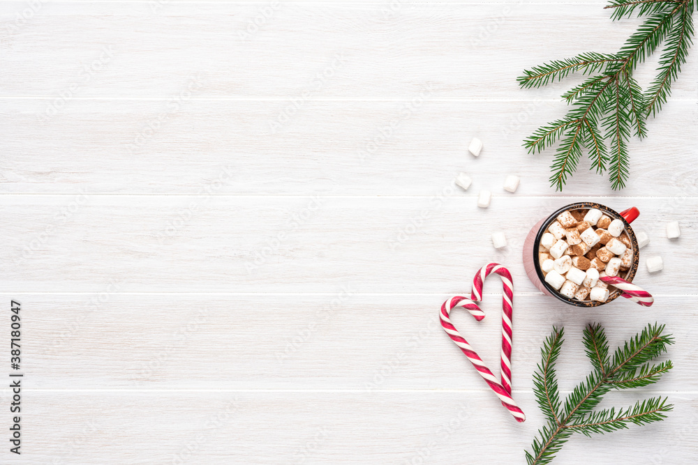 Obraz premium Hot cocoa with marshmallows and candy canes on white wooden slatted background. Copy space, top view
